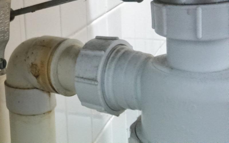 White plastic drain trap and pipes under a sink